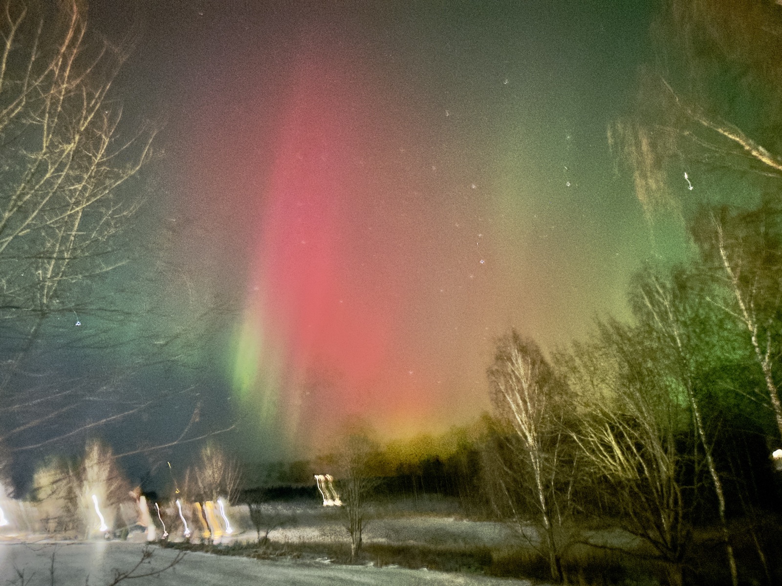 Red green aurora borealis pillars blazing over frozen Finnish lake Rovaniemi